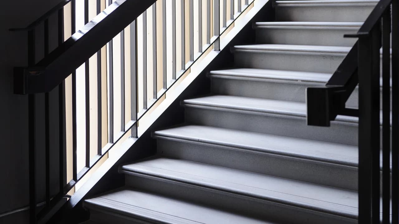 A modern staircase with a black iron railing and handrail